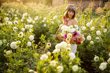 Portrait of a woman with lots of freshly picked up colorful dahlias and lush amaranth flower on...