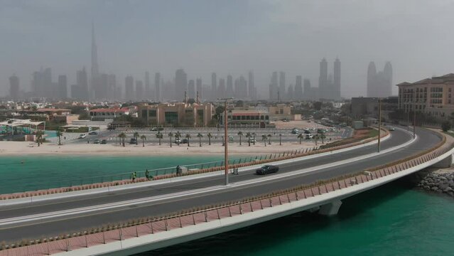 A drone flies over a car traveling on a bridge