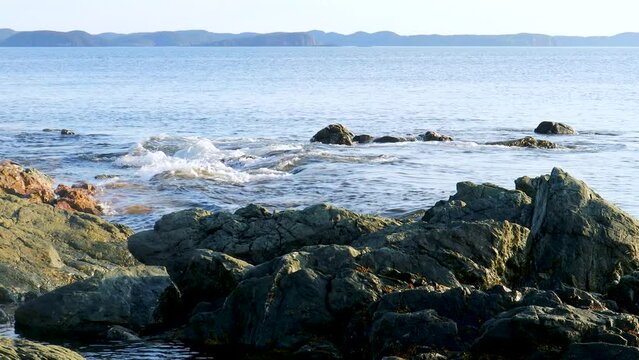 Gentle waves caress the rocks near a rugged shoreline.