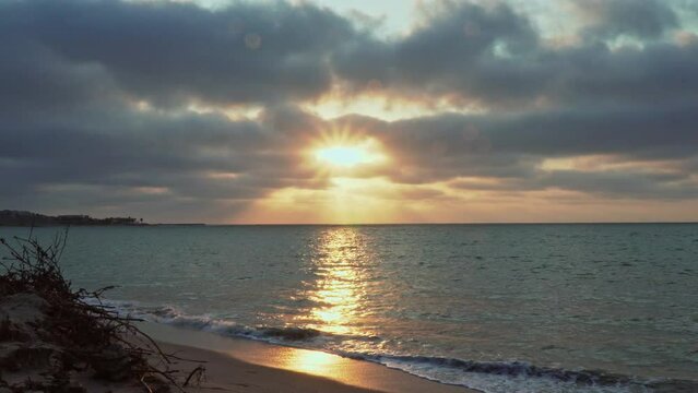 At Zorritos Beach in Tumbes, Peru, the sun is setting in the horizon as the water of the sea washes up at the shore.