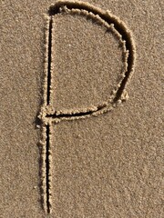 On the beach in the sand is carved the letter P