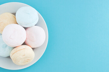 Marshmallows on  white plate. Blue background. View from above. Place for text.