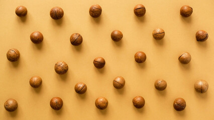 Macadamia nuts pattern. Whole nuts on a brown background