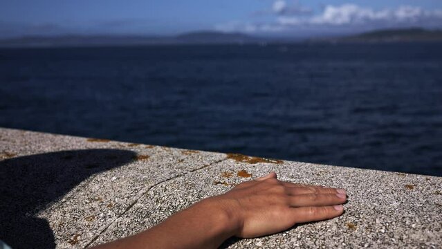 A woman's hand makes flapping movements on a stone surface.