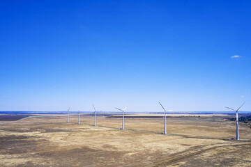 wind power plant in the steppe against the blue sky shooting from a drone