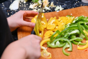 Yellow and green peppers cut into small pieces lie on a cutting board in the kitchen.