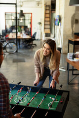 Colleagues having fun at work. Businessman and businesswoman playing table soccer.