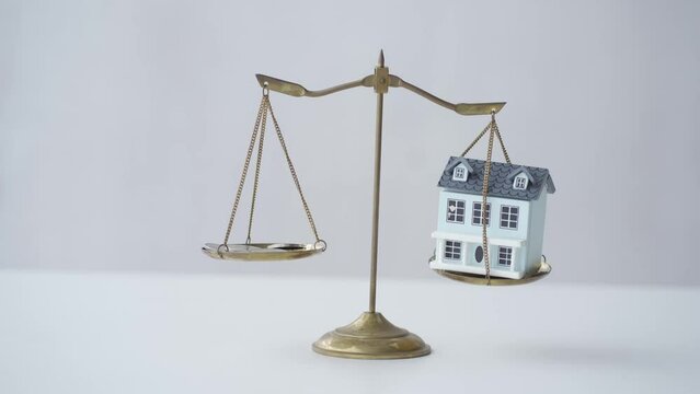 house and coins on golden scales real estate law concept