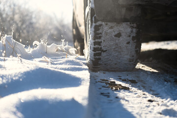 Car wheels snow close-up. Driving on a winter road. Winter tires shooting from a lower angle. The concept of travel, traffic safety, traveling by car. Bright sunny landscape. Snow sparkles in the sun