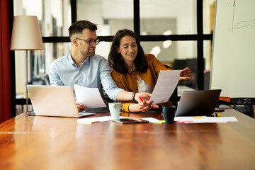 Fototapeta premium Colleagues in office. Businesswoman and businessman discussing work in office.