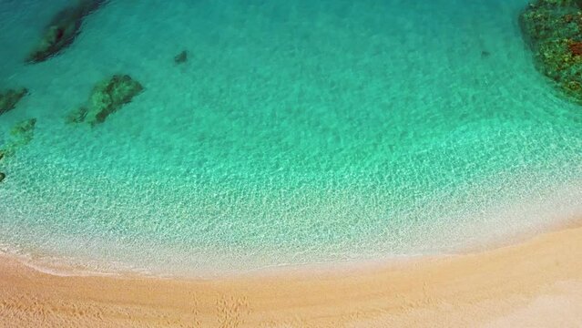 Aerial top down view of idealistic beach with clear turquoise water and yellow sand. The cleanest warm sea of the coast of Greece. Secluded tropical beach, summer travel destination, sea lagoon