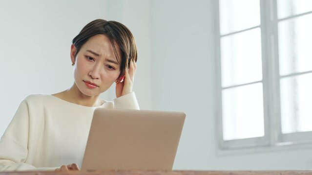 ノートパソコンを見ながら悩む女性