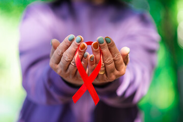 AIDS awareness.Caucasian woman hold red ribbon.Blurred background.World AIDS day concept.