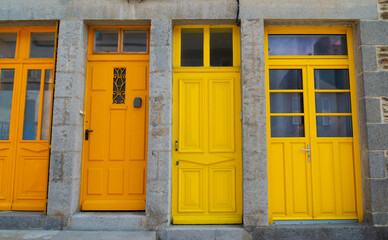 Colorful entrance doors, yellow and orange, in a traditional village of Brittany, France.