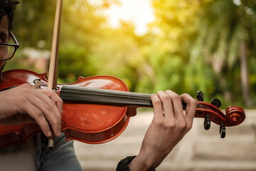 Close up of hands playing the violin outdoors. Violinist artist playing a melody outdoors, Portrait...
