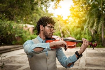 Portrait of man playing violin at sunset. Close up of violinist man playing in the street....