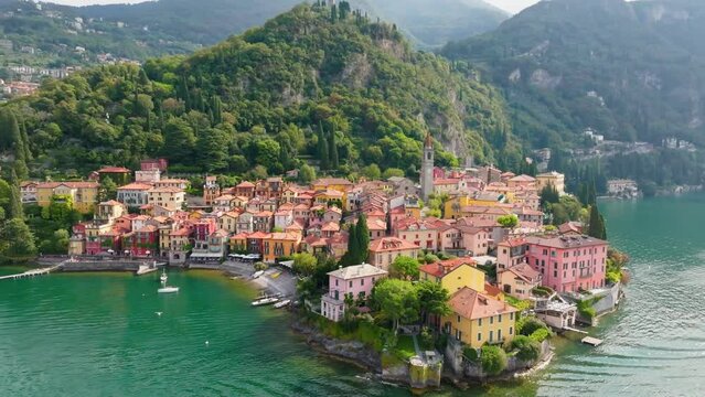 Flying over colorful houses of Varenna village on Lake Como, Italy. Summer luxury tourism landmark romantic honeymoon travel destination. Aerial shot ol old town Varenna on the coast of Lake Como