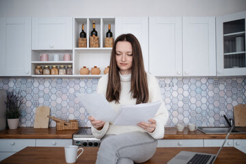 woman with business documents sitting on the kitchen table .