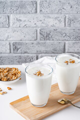 Kefir, buttermilk or yogurt with granola. Yogurt in glass on light background. Probiotic cold fermented dairy drink. Gut health, fermented products, healthy gut flora concept. Copy space