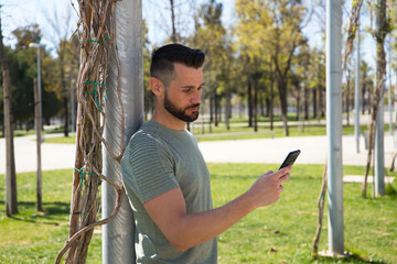 Handsome young blue-eyed gay man is consulting his mobile phone. The man is happy. Email, social networking, apps, telecommunications, video calls.