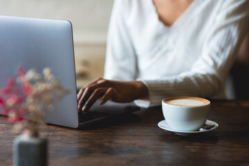 latte coffee cup Asian woman working with laptop in a cafe