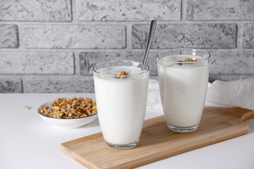 Kefir, buttermilk or yogurt with granola. Yogurt in glass on light background. Probiotic cold...