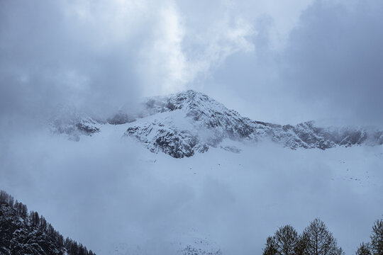 The snow-capped and cloud-covered peaks of the Val di Mello, during a spring day, near the town of San Martino, Italy - May 2022.