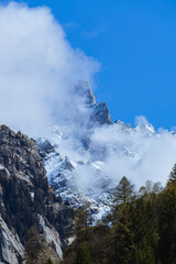 The snow-capped and cloud-covered peaks of the Val di Mello, during a spring day, near the town of San Martino, Italy - May 2022.