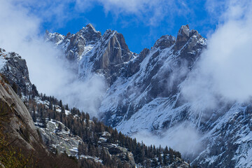 the mountains of val masino and val di mello with fresh snow, during a sunny day, near the town of...
