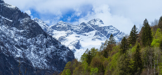 Fototapeta na wymiar the mountains of val masino and val di mello with fresh snow, during a sunny day, near the town of San Martino, Italy - April 2022.