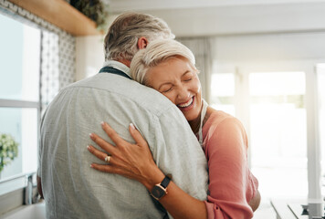 Hug, love and safe with a senior couple hugging or embracing in the kitchen of their home together....