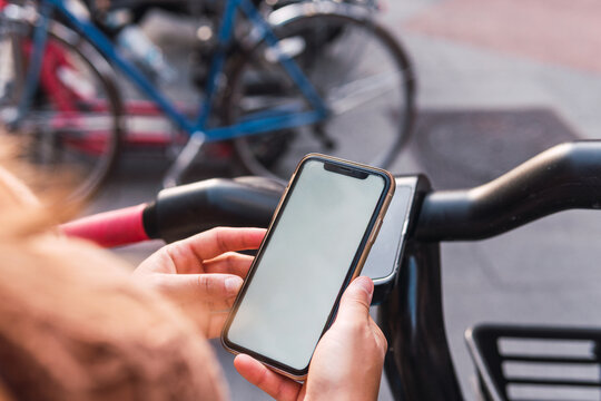 Close-up image of the hands of an unrecognizable woman using her phone terminal to unlock an electric bike for rent in the big city of Madrid.