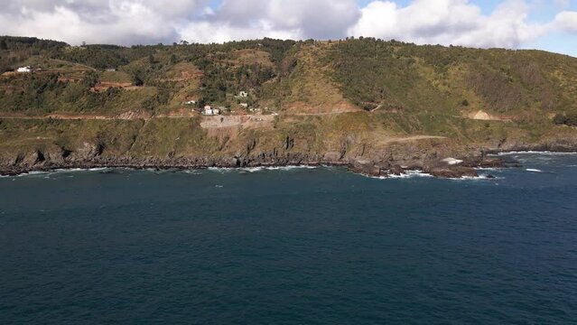 Aerial circing shot of the coastline in a cliffside taken during the day in Chile
