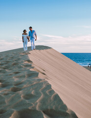A couple walking at the beach of Maspalomas Gran Canaria Spain, men and woman at the sand dunes...