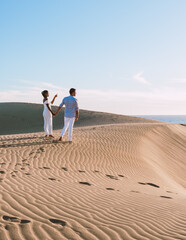 couple walking at the beach of Maspalomas Gran Canaria Spain, men and woman at the sand dunes...
