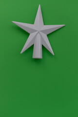 Vertical Christmas background. On a green background, a white star at the top of the photo. New Year layout. Minimalism. Card. Place for text.