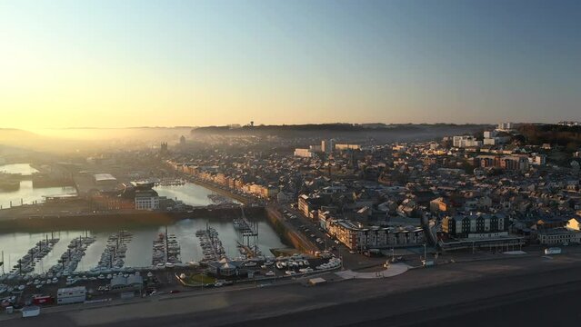 Aerial drone view of the coastal cliffs and city of F&eacute;camp at sunrise in Normandy - France. Harbor city with chalk cliffs