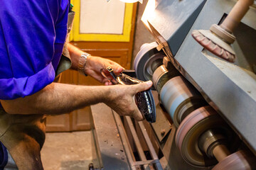 Traditional shoe repair machine, polishing of women's heels.