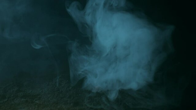 A hand in fumes of smoke emerges from the black earth. Halloween background.