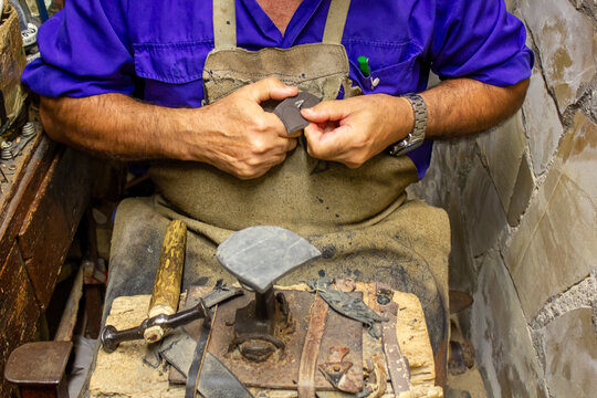 Traditional shoe repair, cutting rubber for heels, with the hammer