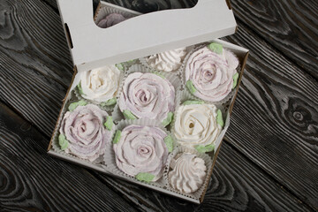 Homemade marshmallows in a gift box. Zephyr flowers. On black pine boards. Taken from above.