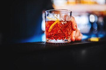 man bartender hand hold negroni cocktail. Negroni classic cocktail and gin short drink with sweet vermouth, red bitter liqueur