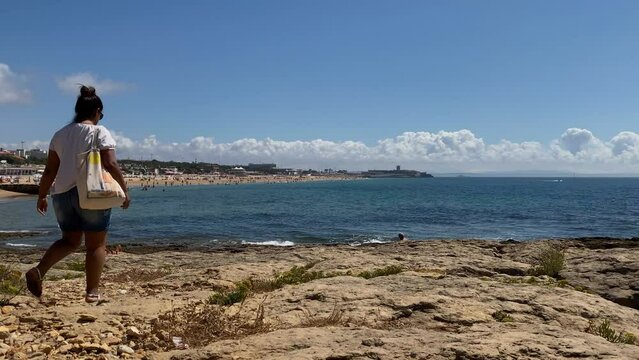 panoramic view of sea waves crashing and people walking alongside the beach