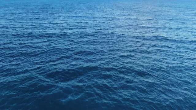 Drone approaching calm blue ocean horizon of the open sea.