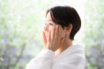 Fototapeta na wymiar 肌を両手で触れる美容に使いやすい女性 左向き　横顔