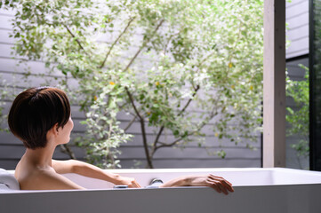Woman relaxing in bath tub, faceless