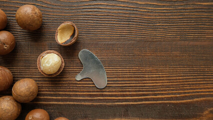 Macadamia nuts and a metal key to open them on a wooden brown background