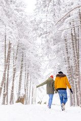 Couple having fun running in the snow while on winter vacation