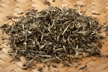 Heap of dried Nepalese White Orange tea leaves close up on a wicker mat 