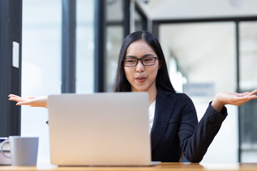 Businesswoman in the office working on laptop and chatting with colleagues via webinar.